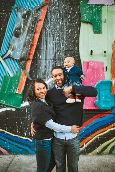Family standing in front of colorful mural