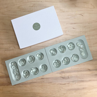 This is a green home decor by Swift and Stone called Sage Green Mancala Game.