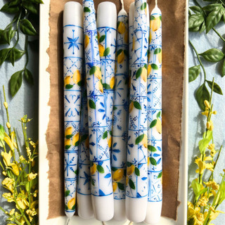 This is a white candles and candle holders by Emily de Moraes called set of 2 amalfi italian tile and lemon taper candles in standard