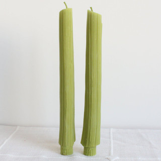 This is a green candles and candle holders by Happy Organics called celery beeswax taper candle pair in standard