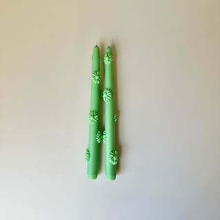 This is a green candles and candle holder by Over By The Moon called Green Daisy Taper Set.