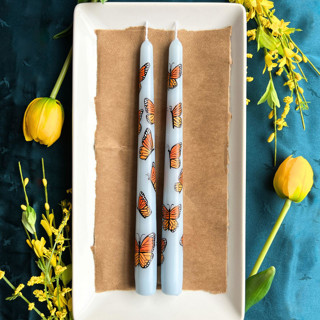 This is a blue candles and candle holders by Emily de Moraes called set of 2 monarch butterfly taper candles in standard