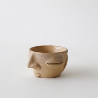 This is a beige decorative objects by Mano Made called face cup - small in standard