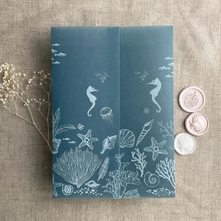 This is a blue vellum wedding invitations by Ivory Invitations called under the sea white ink printed on steel blue colored vellum wrap for 5x7 card  | pack of 10 in standard