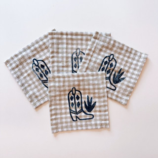 This is a beige tableware by Julie Peach called cowboy boot on gingham cocktail napkin set in standard