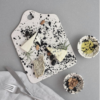 This is a black tableware by OWO Cerámica called handmade rock ceramic cheese board - black & white splatterware in standard