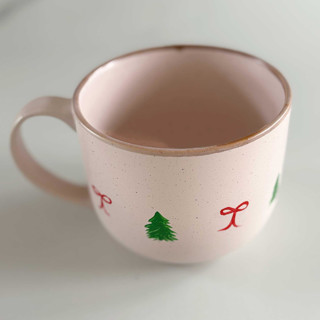 This is a pink tableware by Nicoletta Savod called hand-painted blush stoneware mug with green christmas trees and dainty red bows in standard