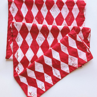 This is a red tableware by Julie Peach called block printed diamonds table runner in standard