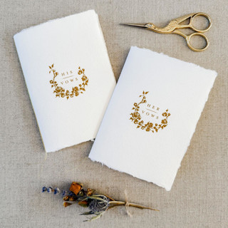 This is a white vow books by Jen Simpson called floral wreath  handmade paper vow book set of two in standard