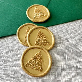 This is a gold wax seals by Maria Ferrer G. called classic gold "merry christmas" tree calligraphy wax seal sticker | set of 10 in standard
