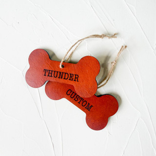 This is a brown holiday decorations by Left Grain called personalized leather dog bone ornament in standard