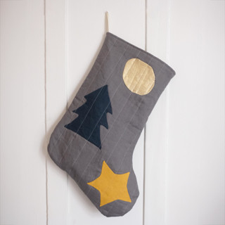 This is a gray holiday decorations by Quiet Goods called charcoal quilted stocking with multi-color appliqué details no.2 in standard