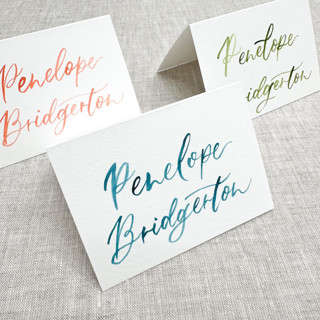 This is a multicolorassorted-colors wedding place cards by Maria Ferrer G. called custom place cards with watercolor lettering | tent place cards with modern calligraphy in standard