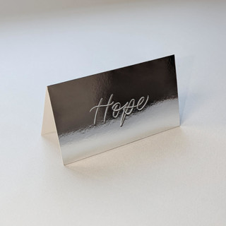 This is a silver wedding place cards by Sam Dubeau called hand debossed place card | silver chrome tent style with first name in standard