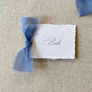 This is a blue wedding place cards by Cotton and Bow called handmade paper place cards with dusty blue bow | set of 10 | custom text in standard