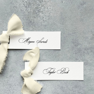 This is a white wedding place cards by Cotton and Bow called slim place cards with ivory bow | set of 10 | custom text in standard